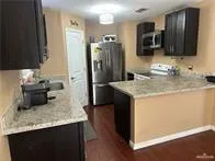 a kitchen with kitchen island granite countertop stainless steel appliances a sink stove refrigerator and a microwave