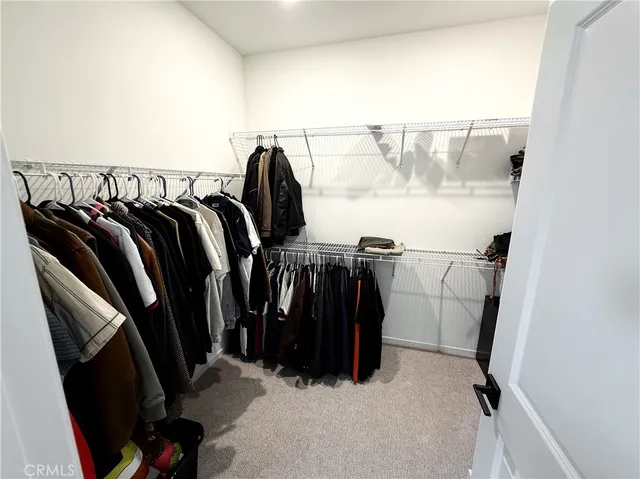 a view of walk in closet with clothes and shoes