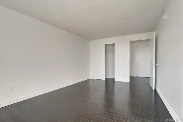 a view of an empty room with wooden floor and closet