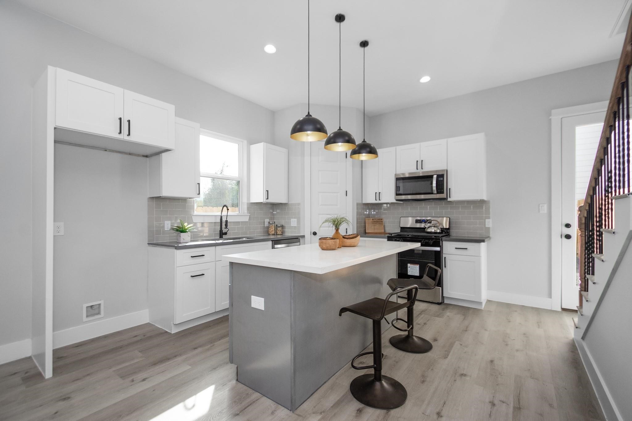 2105 Sam Wilson Street, Unit A Houston, TX 77020 - Photo 4 of 20 a kitchen with kitchen island a sink a stove a center island stainless steel appliances and cabinets
