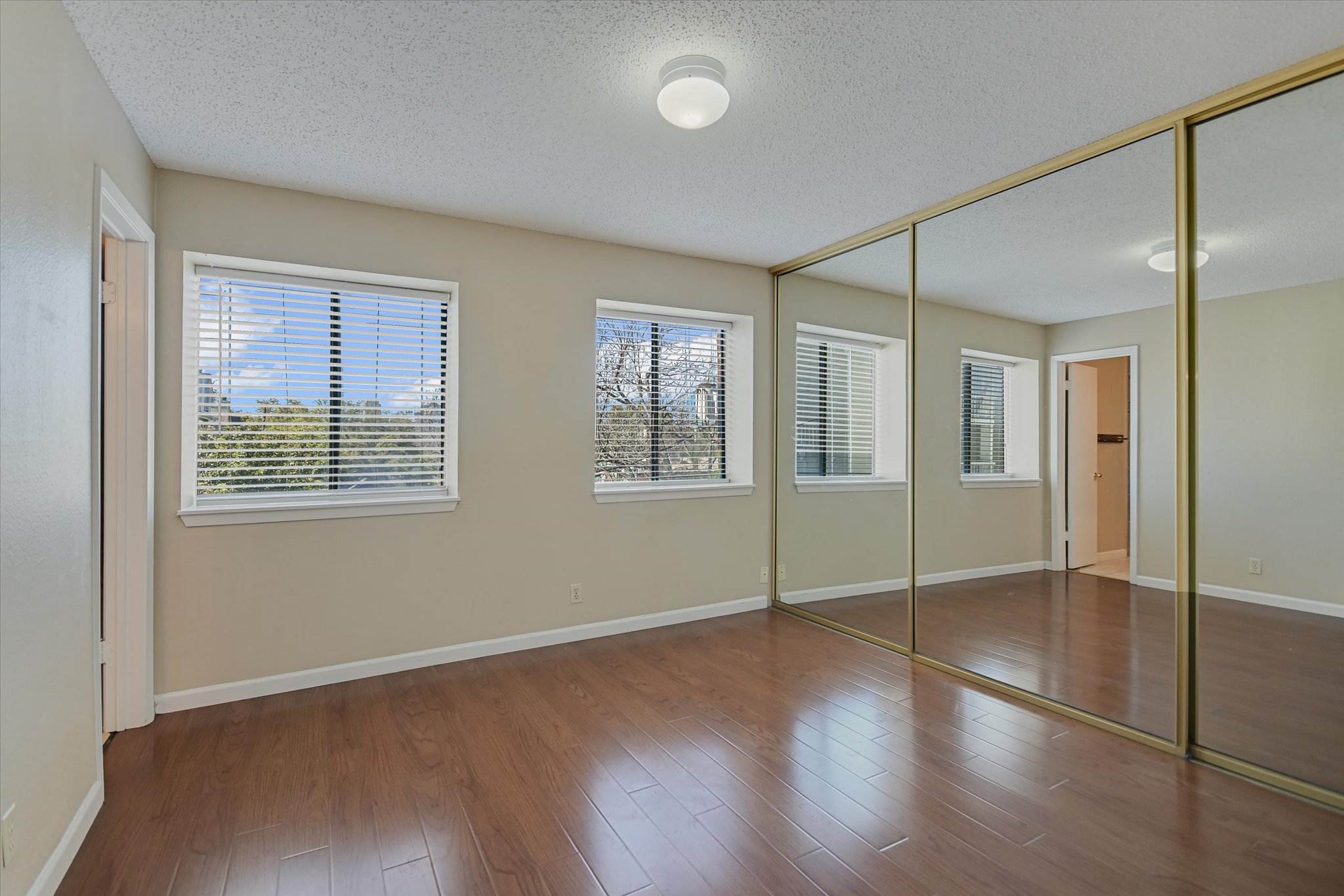 3115 Helms Street, Unit 112 Austin, TX 78705 - Photo 8 of 13 an empty room with wooden floor and windows