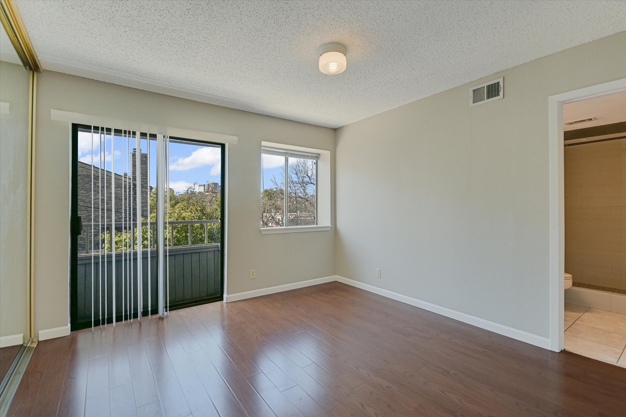 3115 Helms Street, Unit 112 Austin, TX 78705 - Photo 10 of 13 an empty room with wooden floor and windows