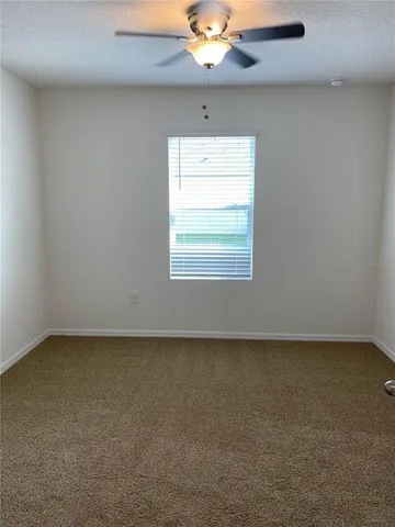 an empty room with a chandelier fan and window
