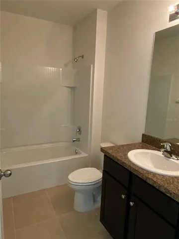 a bathroom with a granite countertop toilet a sink and a bathtub