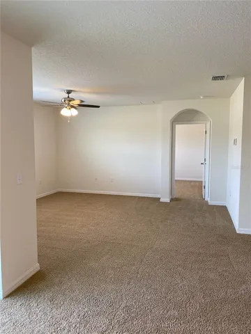 a view of an empty room with a chandelier fan