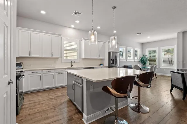 a kitchen with stainless steel appliances granite countertop a sink a stove a refrigerator and island with wooden floor