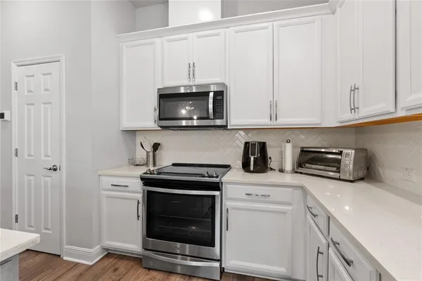 a kitchen with stainless steel appliances granite countertop grey cabinets a stove a sink and dishwasher