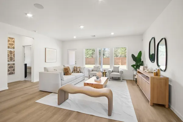 a living room with furniture large window and wooden floor