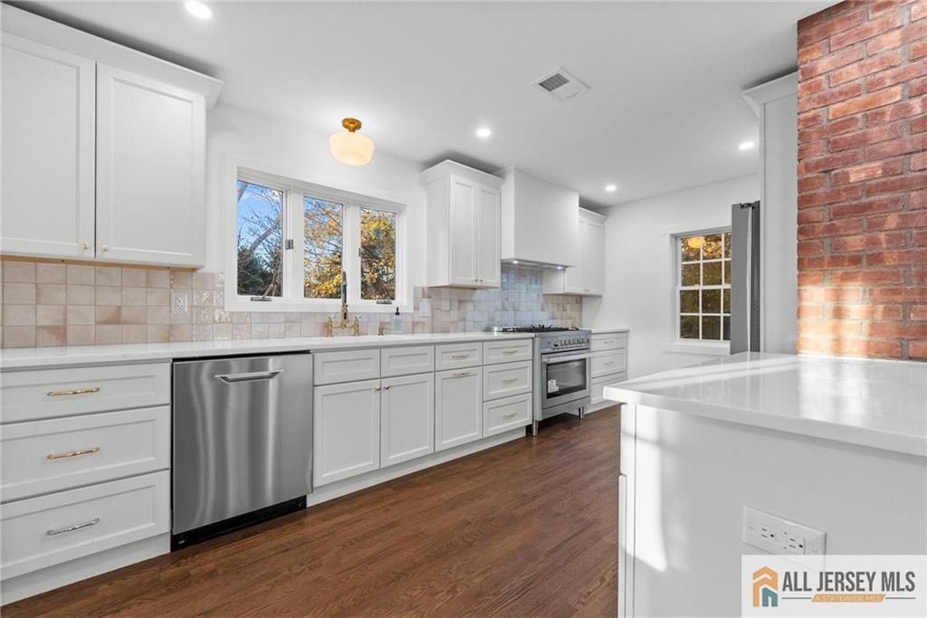143 Maple Avenue Chester, NJ 07930 - Photo 33 of 52 a kitchen with stainless steel appliances granite countertop a stove a sink and white cabinets with wooden floor