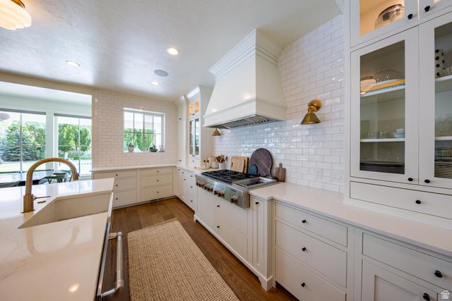 630 East Center Street Alpine, UT 84004 - Photo 26 of 115 Gourmet kitchen featuring a professional-grade range, custom range hood, subway tile backsplash, white shaker cabinetry with glass-front uppers, and stone countertops