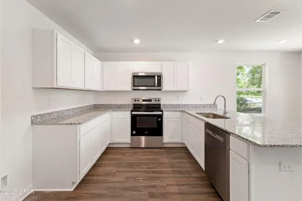 a kitchen with granite countertop a stove top oven a sink dishwasher and a refrigerator with wooden floor