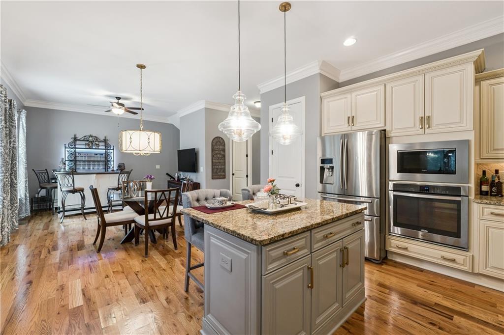 217 Trecastle Square Canton, GA 30114 - Photo 24 of 43 a kitchen with stainless steel appliances granite countertop a stove a refrigerator a kitchen island a dining table and chairs with wooden floor