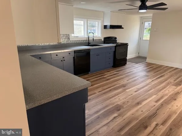a kitchen with a sink a stove cabinets and wooden floor