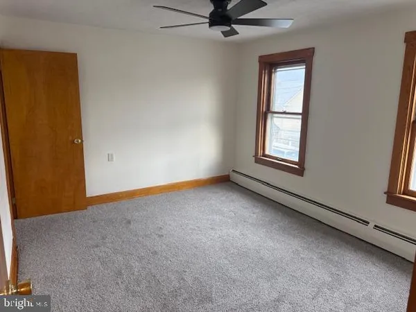 an empty room with windows and fan