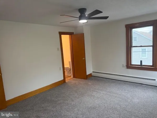 an empty room with windows and fan