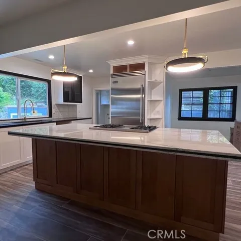 a kitchen with kitchen island granite countertop a sink and a wooden floor