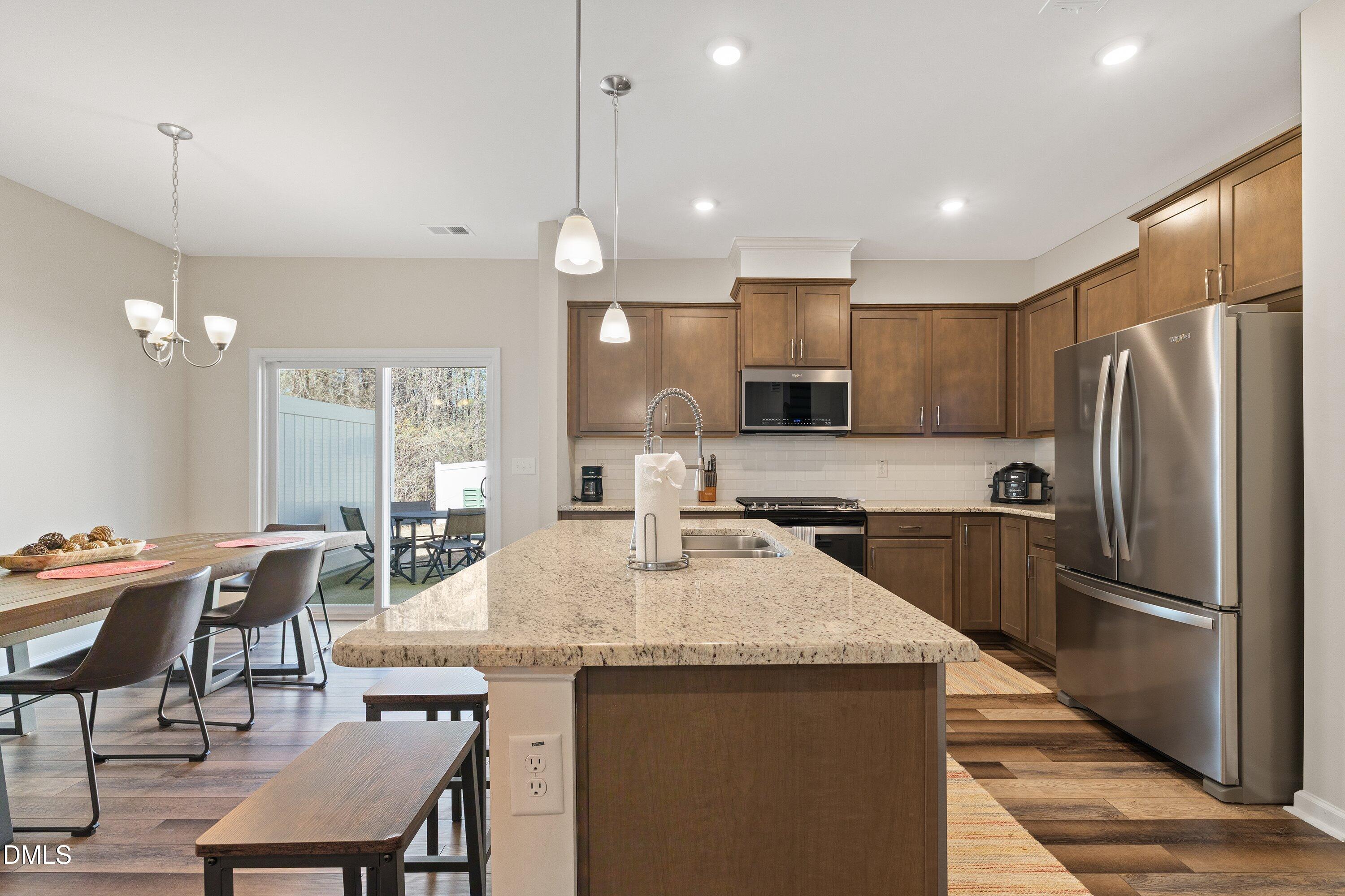 1004 Everglades Way Durham, NC 27713 - Photo 16 of 40 a kitchen with granite countertop a table chairs microwave and refrigerator