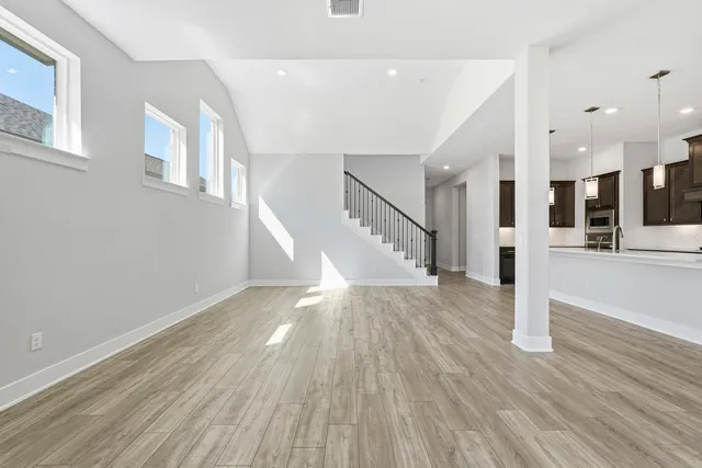 a large kitchen with stainless steel appliances kitchen island granite countertop a stove a refrigerator a sink and a wooden floors