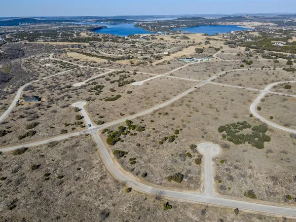 a view of a dry field with trees in the background