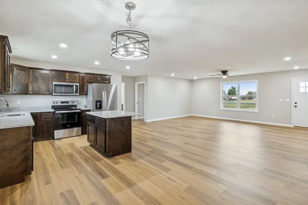 a large kitchen with stainless steel appliances a large counter top a stove and a wooden floors