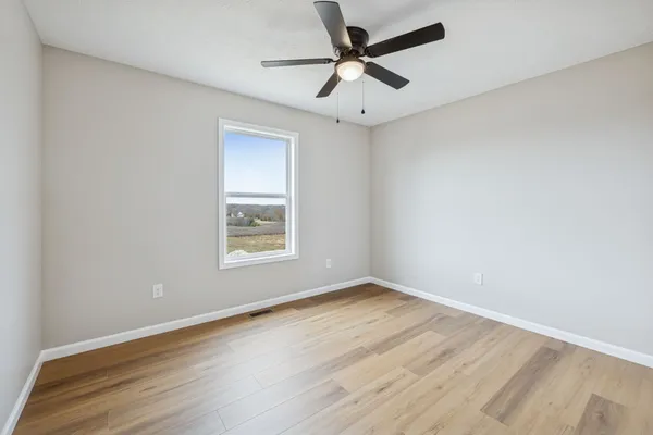 an empty room with a window and a fan
