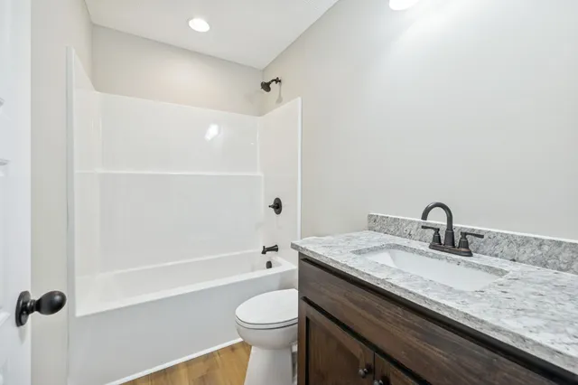 a bathroom with a granite countertop sink a toilet and shower