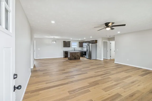 a view of kitchen and empty room with wooden floor