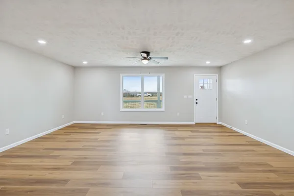 a view of an empty room with wooden floor and a window