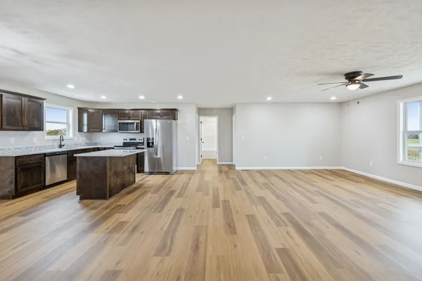 a open kitchen with kitchen island a stove a sink dishwasher and a oven with wooden floor