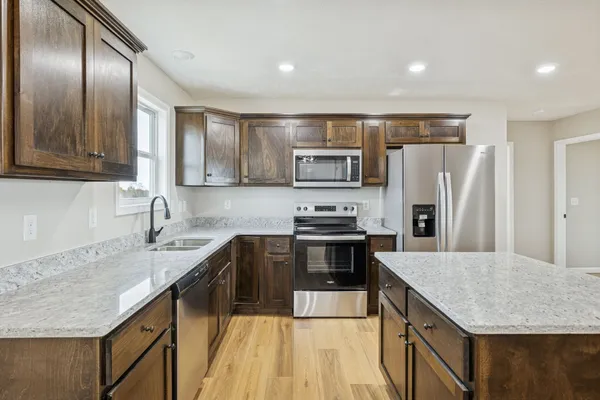 a kitchen with kitchen island granite countertop stainless steel appliances cabinets a sink and a counter top space