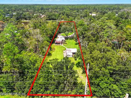 an aerial view of residential houses with outdoor space and trees