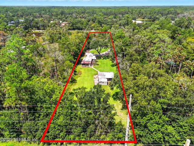 an aerial view of residential houses with outdoor space and trees