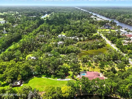 an aerial view of residential houses with outdoor space and trees