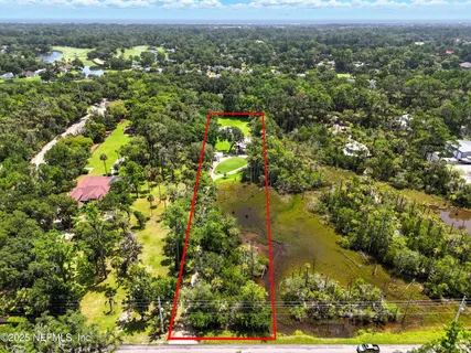 an aerial view of residential houses with outdoor space and trees