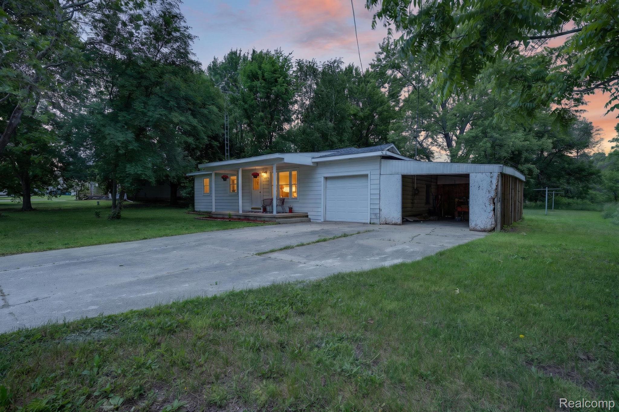 9288 Hilda Lane Flushing, MI 48433 - Photo 5 of 50 White siding home featuring a covered front porch, attached garage with a white garage door, and a connected carport