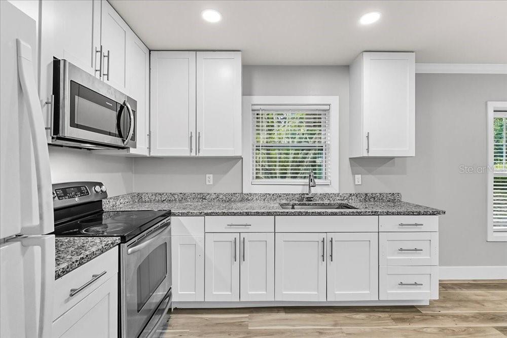 5804 Wolf Road Orlando, FL 32808 - Photo 4 of 24 a kitchen with stainless steel appliances granite countertop white cabinets granite counter tops and a stove