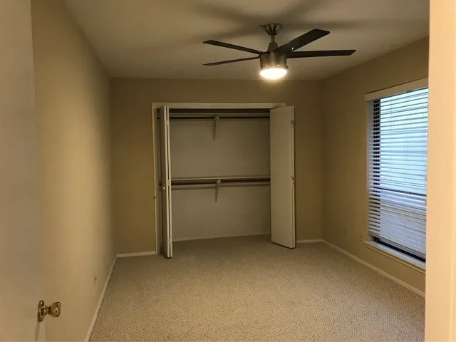 an empty room with a ceiling fan and carpet