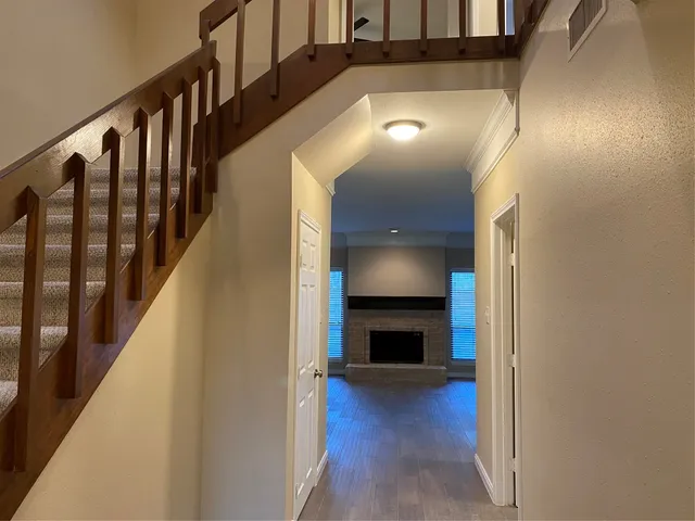 a view of an empty room with wooden floor and a fireplace
