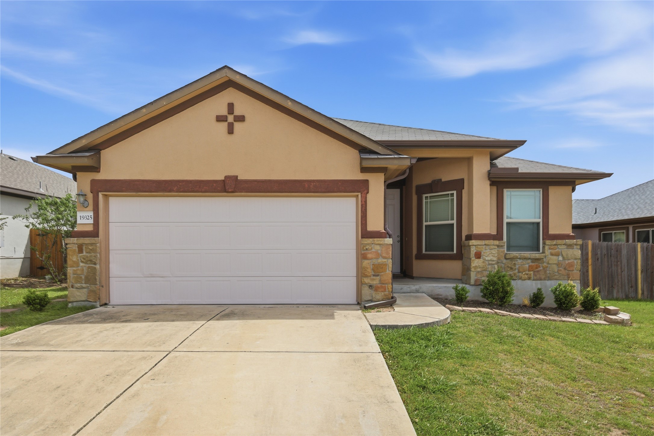 View of front facade with a garage, stone siding, stucco siding, and driveway