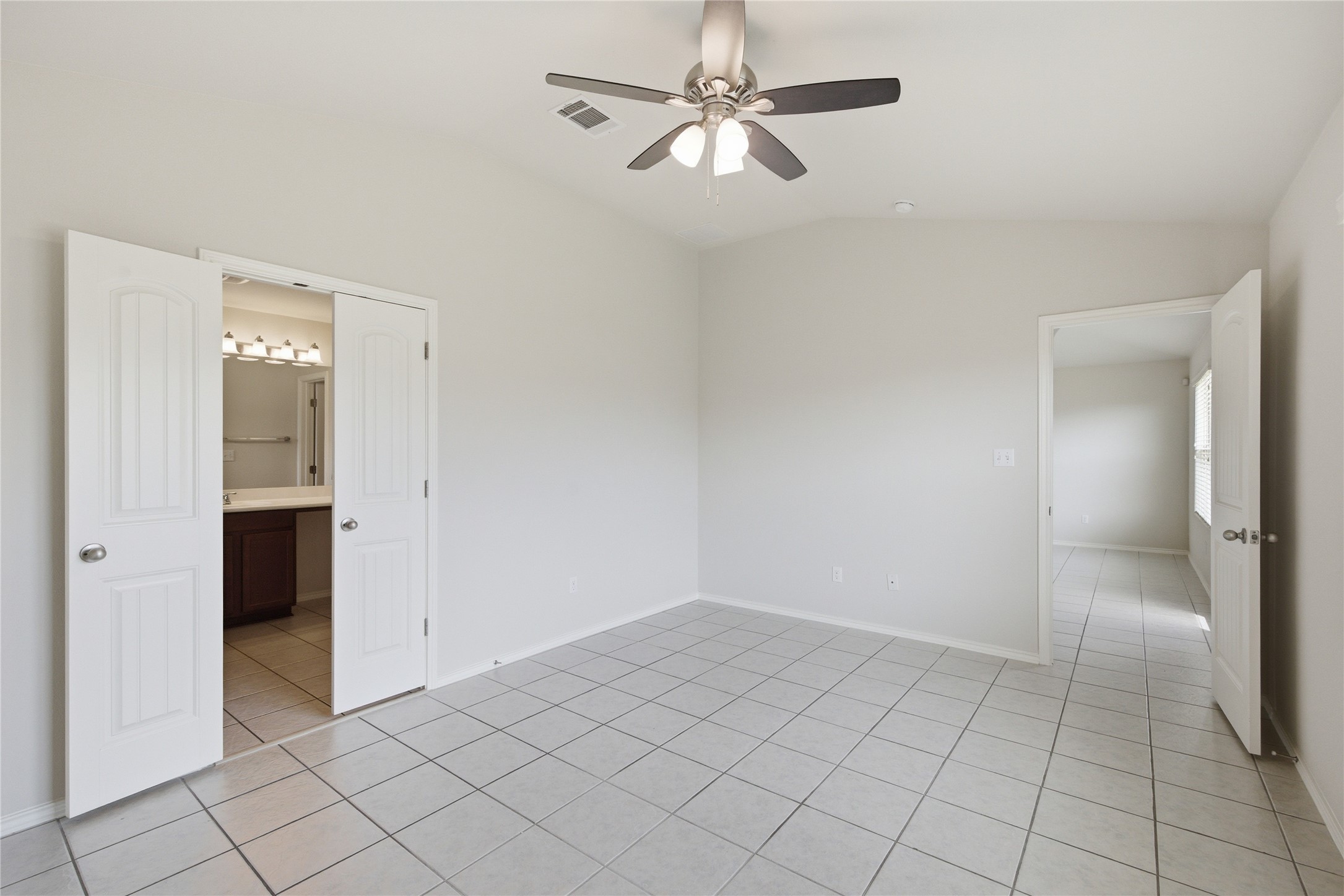 19325 Stokes Lane Pflugerville, TX 78660 - Photo 9 of 24 Unfurnished bedroom with light tile patterned flooring, lofted ceiling, ceiling fan, and connected bathroom