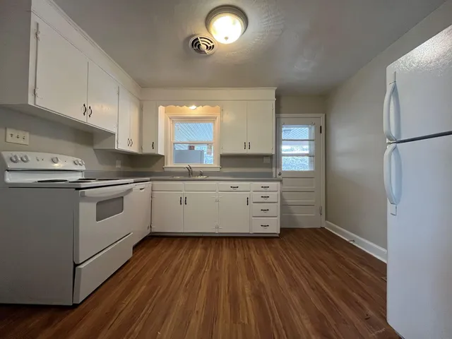 a kitchen with granite countertop a sink cabinets stainless steel appliances and a window