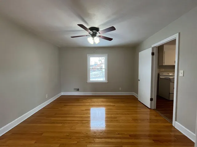 a view of empty room with wooden floor and fan