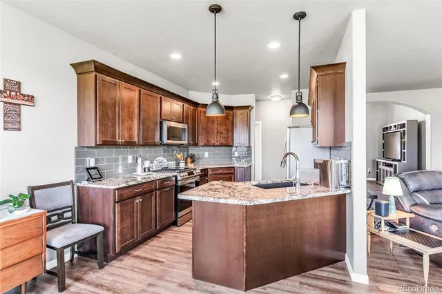 a kitchen with stainless steel appliances granite countertop a sink a stove and a wooden floors