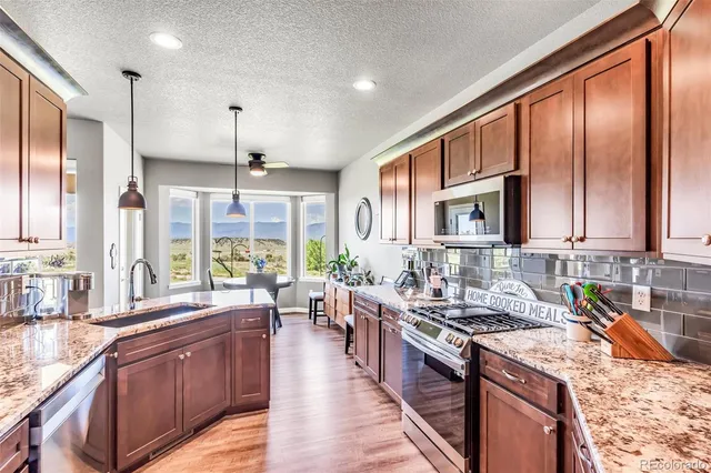 a large kitchen with stainless steel appliances granite countertop a large window and a counter space