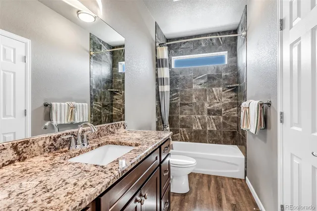 a bathroom with a granite countertop sink toilet and shower