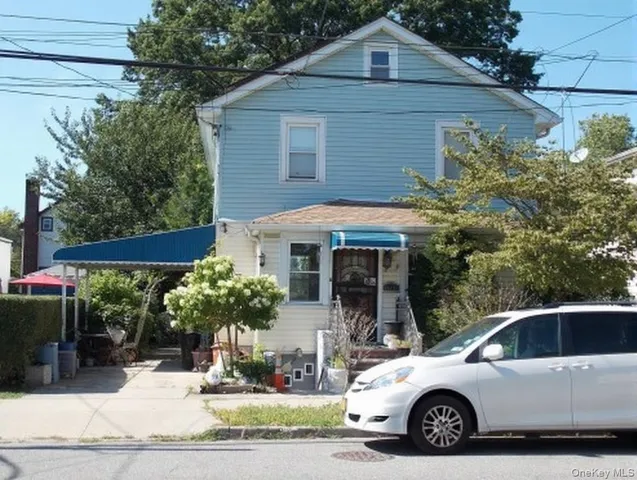a view of a white house with large windows and flower plants