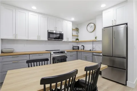 a kitchen with stainless steel appliances granite countertop a stove a refrigerator a sink a dining table and chairs