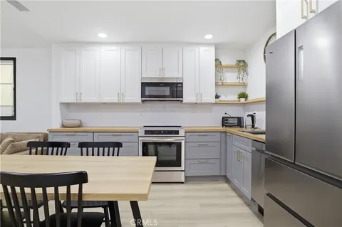 a kitchen with stainless steel appliances granite countertop a stove a sink dishwasher a refrigerator and a microwave oven with wooden floor