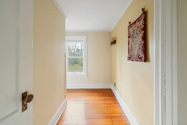 a view of a hallway with wooden floor and a window