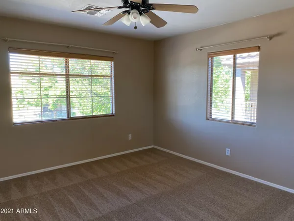 an empty room with windows and chandelier fan